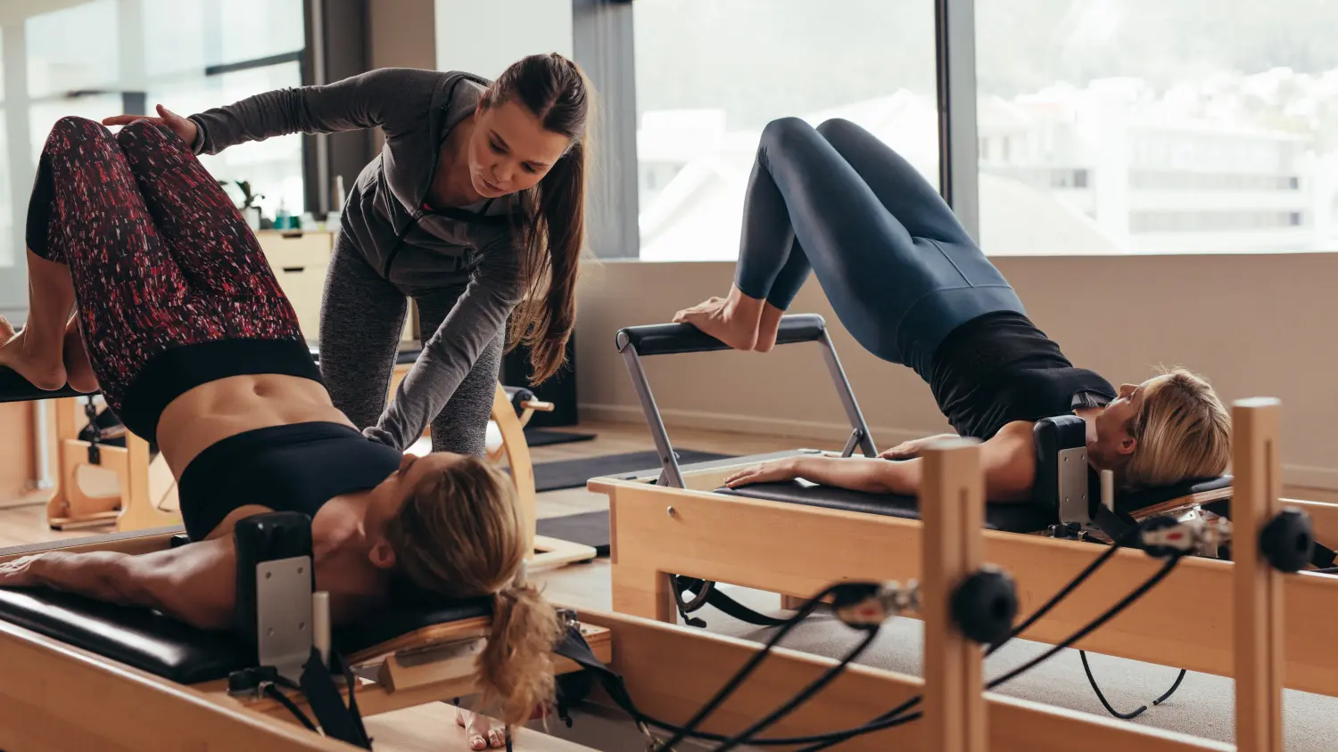 Pilates-Trainerin hilft einer Pilates-Frau beim Training